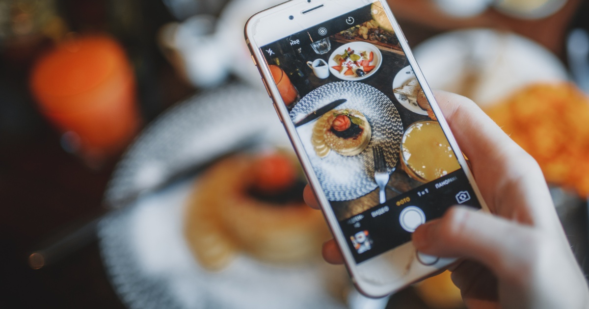 Title image that indicates that food photos can generate up to 30% higher sales. Shows a picture of someone taking a photo of food with their cell phone.
