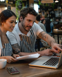 Two restaurant owners reviewing their digital customer data to plan their promotions.